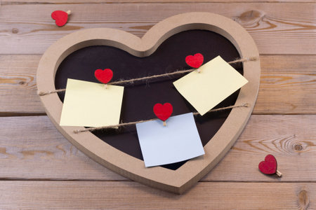 heart shaped frame with note paper on wooden backgroundの写真素材