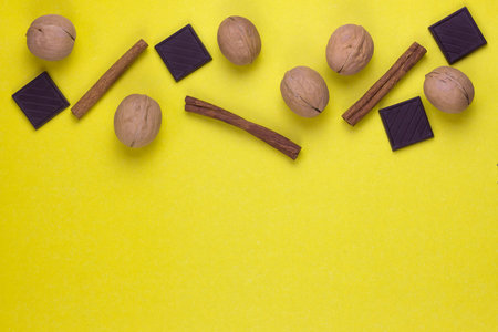 cinnamon, nuts and pieces of chocolate on a yellow background. Flat lay. copy space