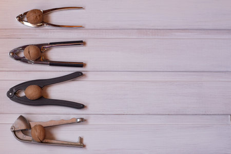 four nutcrackers with nuts on a white wooden background. view from above. copy space.の写真素材