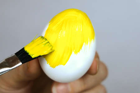 Paint the eggs with yellow paint. Preparing for Easter. Selective focus. Close-upの写真素材