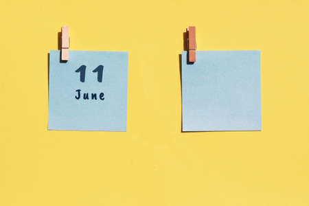 June 11st. Day of 11 month, calendar date. Two blue sheets for writing on a yellow background. Top view, copy space. Summer month, day of the year conceptの写真素材