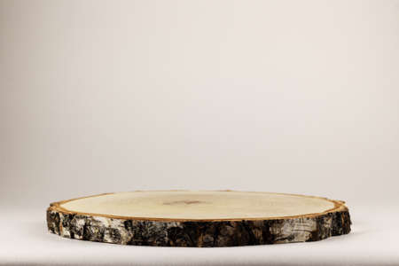 Round flat wooden saw cut of the cylinder on a light background. Geometric podium for cosmetics. Empty showcase for demonstration.の写真素材