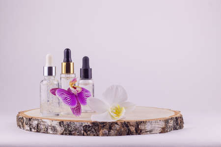 Glass bottle with serum and oil on a wooden round podium. Spa care concept. Natural organic cosmetics.の写真素材