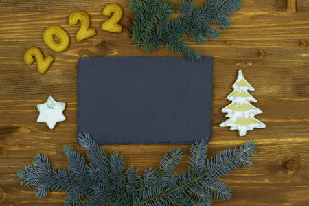 Christmas, New Year. Composition with numbers 2022, gingerbread cookies and chalkboard on wooden...
