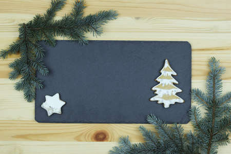 Christmas composition with fir branches and slate board on wooden background, place for text.の写真素材