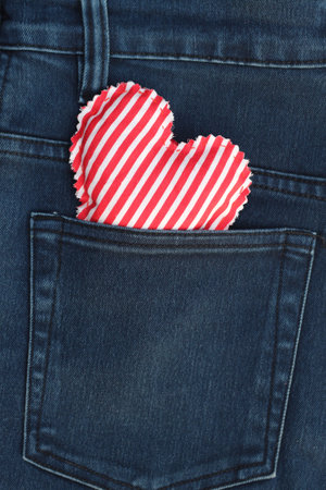 Red handmade heart in jeans pocket. View from above