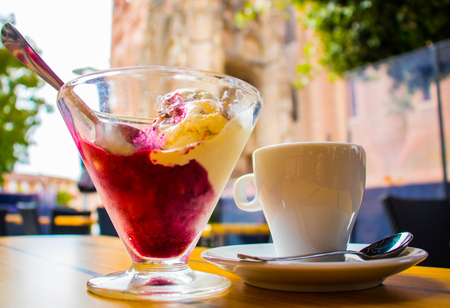 Ice cream and a cup of coffee in the cafe on the background of the historic part of the city.の写真素材