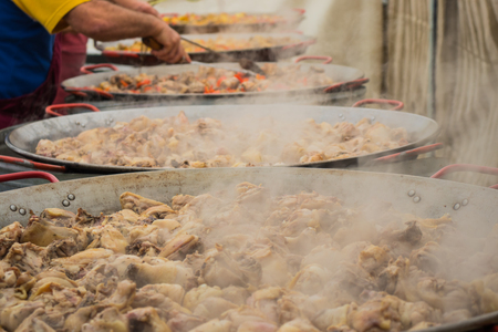 Chicken meat is steamed in giant pan to prepare a collective paella.の写真素材