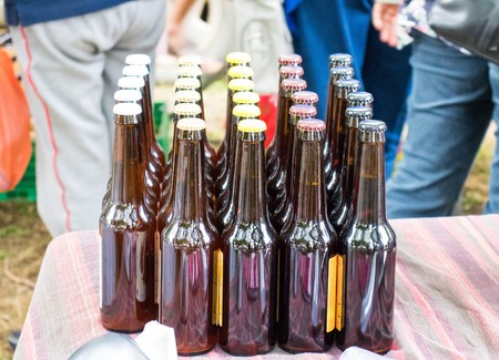 Small bottles of beer are evenly arranged on the table at the rural fair.の写真素材