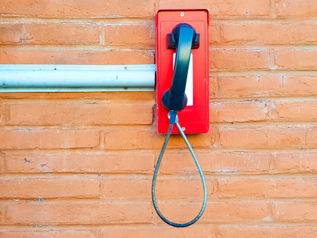 Red phone intercom on a brick wall.の写真素材