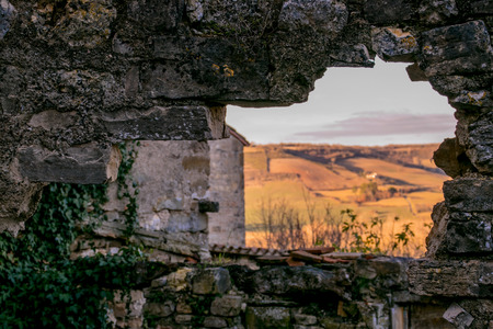 Through a hole formed in an ancient stone wall, you can see a beautiful rural landscape.の写真素材