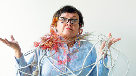 An elderly woman in glasses is tangled in wires.の写真素材