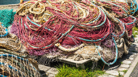 Pile of old and used fishing nets colored, floating and blue rope on the quay