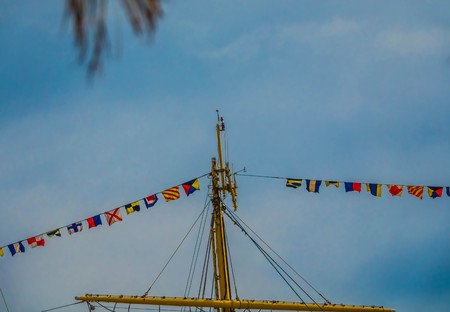 The masts of an old sailing ship with colorful ornaments against the sky.の写真素材