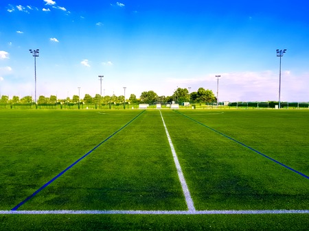 empty green football field in the open air under blu skyの写真素材