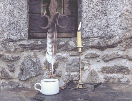 a cup of coffee, glasses, a pen for ink, a candle in a candlestick against the backdrop of a stone...