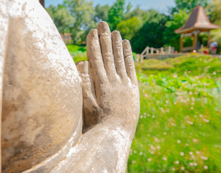 The hands of the statue are laid with palms for meditation against the background of the blured Asian landscapeの写真素材
