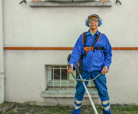 Professional gardener with edge trimmer in the home gardenの写真素材
