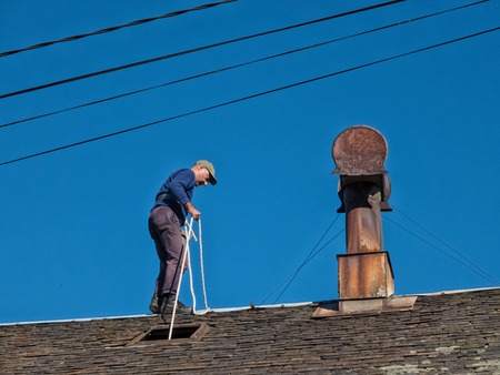 A man works on the roof of an old village house with slate tiles.の写真素材