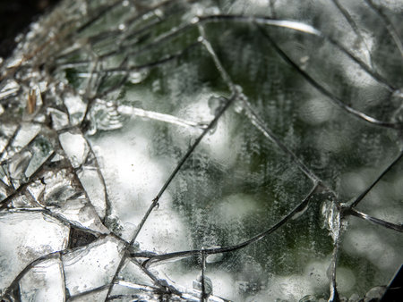 Texture of broken shards of the rearview mirror of the car on an asphalt road.