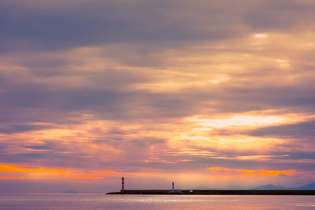 Seascape with a pier and a lighthouse under a beautiful sky in pink tones