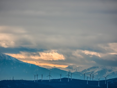 Landscape with wind turbines against the background of snow-capped mountains.の写真素材