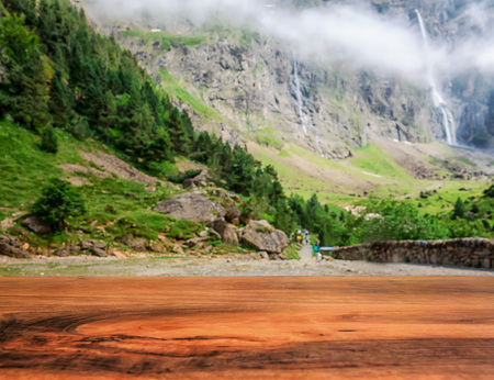 Empty surface of a wooden table overlooking the path leading to the mountains to the waterfall.の写真素材