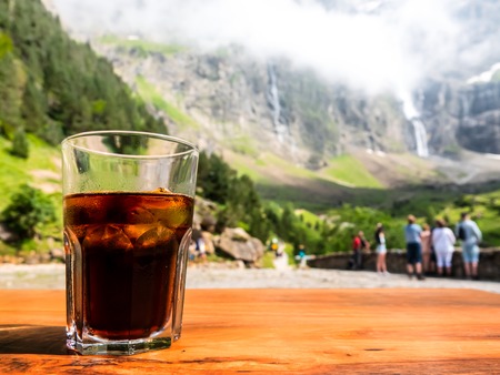 Empty surface of a wooden table with a drink overlooking the path leading to the mountains to the waterfall.の写真素材