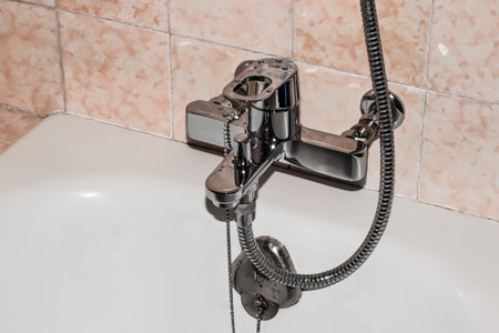 Water tap with a hose from the shower over the bath in the bathroom