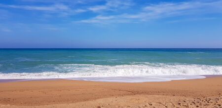 The sea is worried and runs onto the sandy shore under sunの写真素材