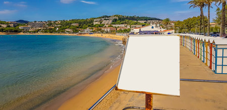 White plate with copy space on the background of a sandy beach multi-colored beach cabins