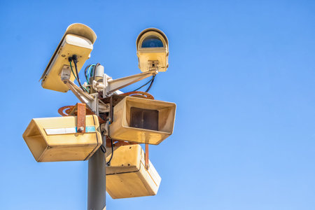 Surveillance cameras in the city on a high pillar against the blue sky