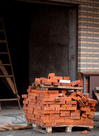 New Red brick stack on the pallet on the building backgroundの写真素材