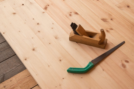Old wooden jointer carpenter tool and metal saw on wooden background.
