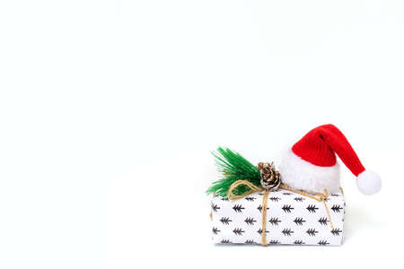 Christmas gift with balls bow on and santa hat on white backgroundの写真素材