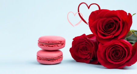 Valentine's Day background. Red roses and French Macaron on pastel blue art paper. Love concept: Valentine's day, birthday, wedding, Women's day. Banner. Copy space for text. close up.の写真素材