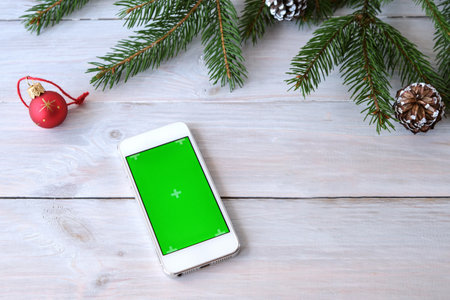 Christmas shopping online with mobile phone with blank green screen on wooden background. Chromakey. Concept: online shopping for Christmas, Christmas gifts. Selective focus. Copy spaceの写真素材