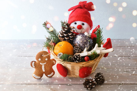 Decorative basket with Christmas decorations, orange and gingerbread. Funny and cute Snowman with New Year's gifts. Winter and Christmas concept. Copy space. Close-up.の写真素材