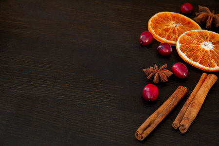 Orange slices, cranberries, cinnamon and anise on a dark background. The idea of winter vitamin...