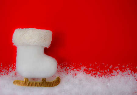 Christmas card with a white skate in the snow. Christmas tree toy on a red background. Flat lay. Copy spaceの写真素材