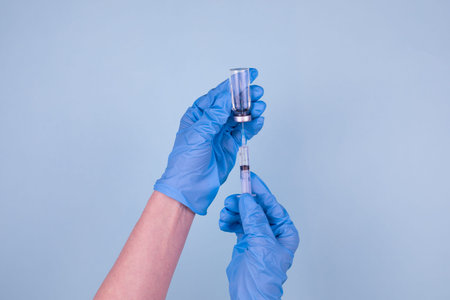 Vaccination against the new . A doctor in blue gloves dials a vaccination drug into a syringe from a...