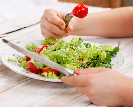 food salad with tomato hands holding fork and knifeの写真素材