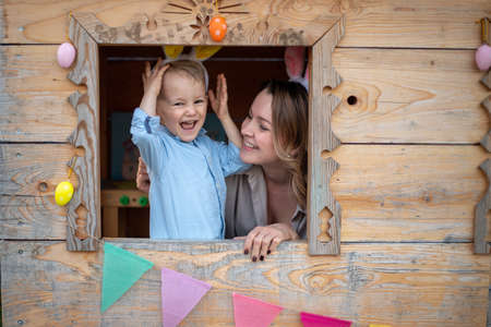 mom and son in bunny ears celebrate easter, play in the playhouse. Happy easter.の写真素材
