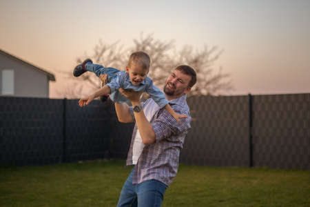 dad playing with his son in the backyard of the house.の写真素材