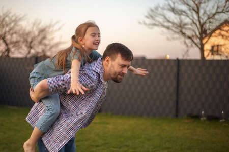 dad playing with his daughter in the backyard of the house.の写真素材
