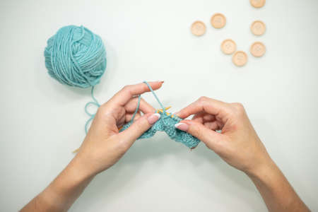 Womens hands knit on a white background. Knitting on knitting needles from wool and cotton. handmade.の写真素材