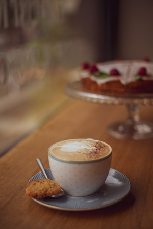 Cup of coffee with a heart pattern in a cup on a saucer on a wooden background in a cafe.の写真素材