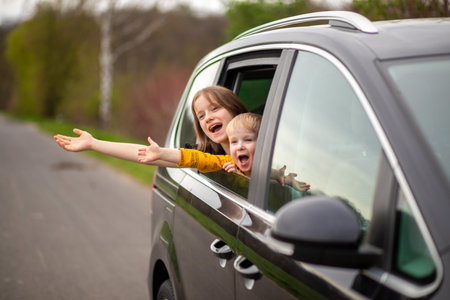 Happy brother and sister looking out car window , rejoice and laughの写真素材