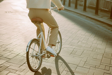 Woman riding a bicycle on city pavement at sunset.の素材