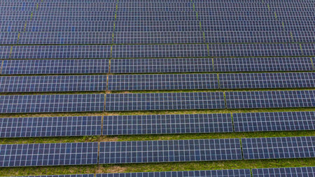 Direct aerial view of solar panel rows on green background.